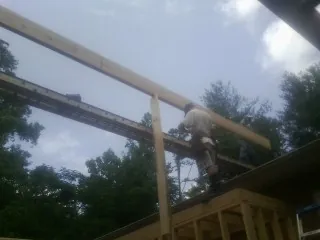 Carpenter setting a ridge beam over a new addition frame — Ice Dam Removal by Roofing Brothers in Graham