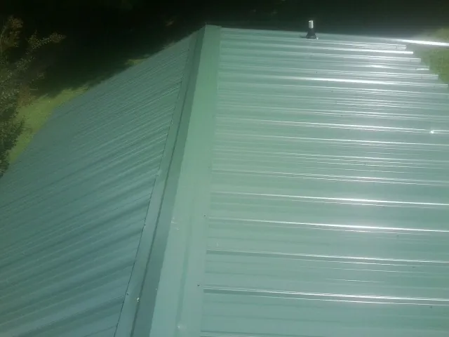 New green metal panels meeting at the ridge of a roof — Flat Roof Repair work by our crew in Graham
