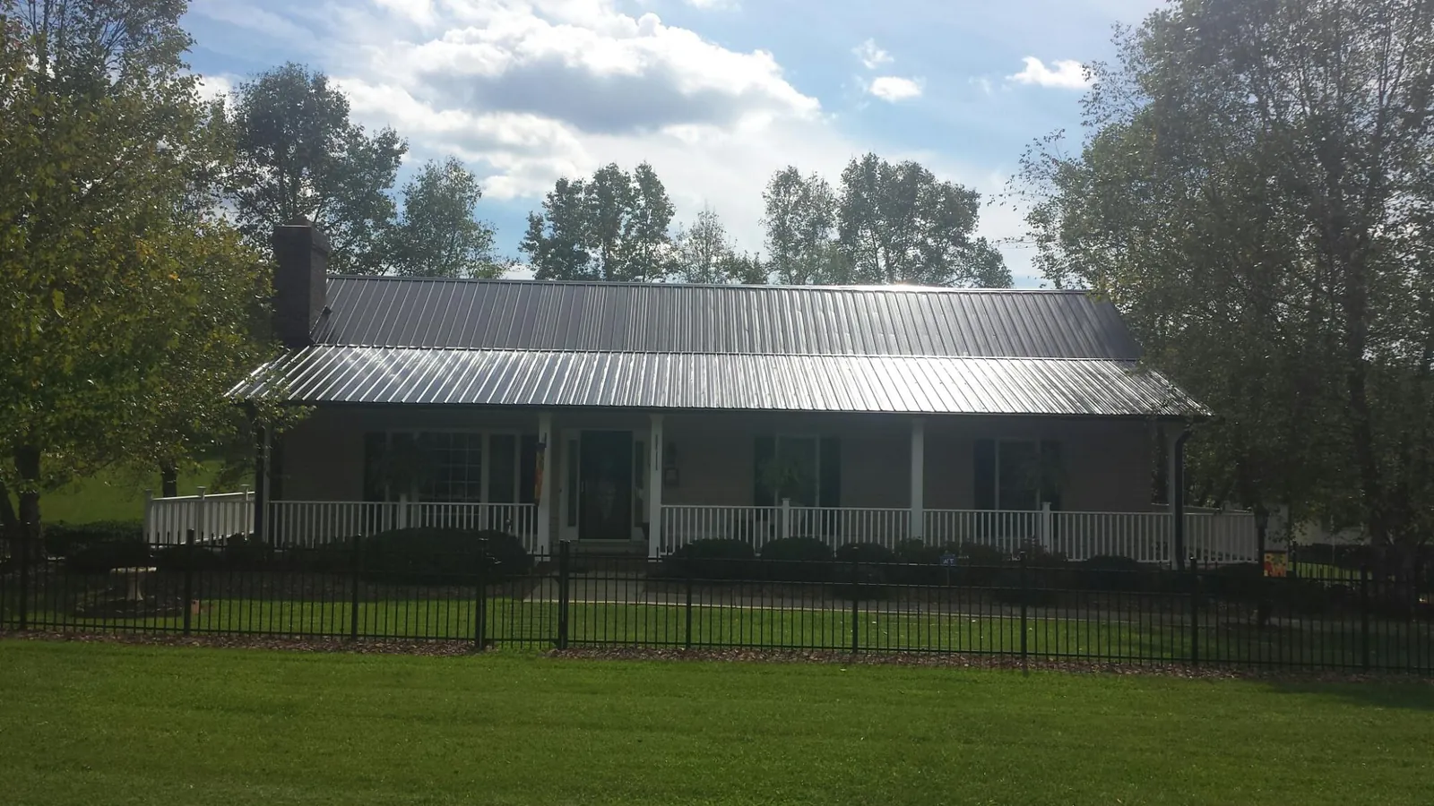 Gray metal roof on a brick ranch with a full width front porch — Gutter Guard Installation work by our crew in Graham