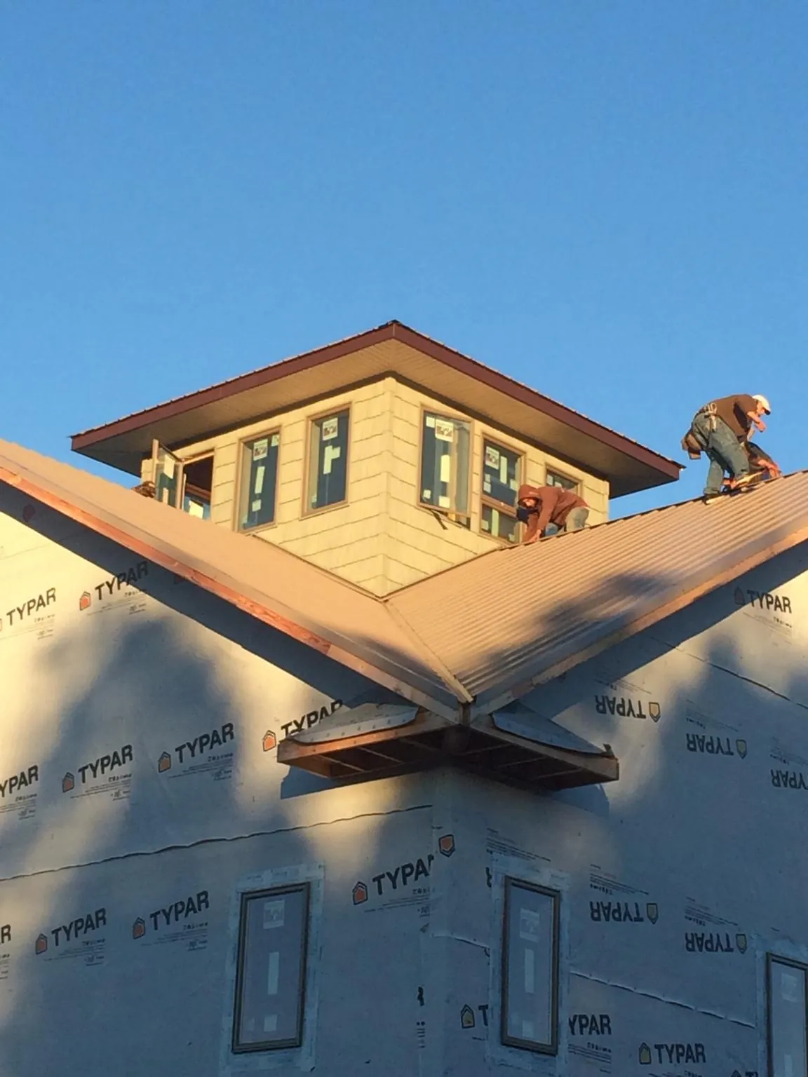 Roofers working around a rooftop cupola on a new metal roof at sunset — Roof Waterproofing in Graham by Roofing Brothers